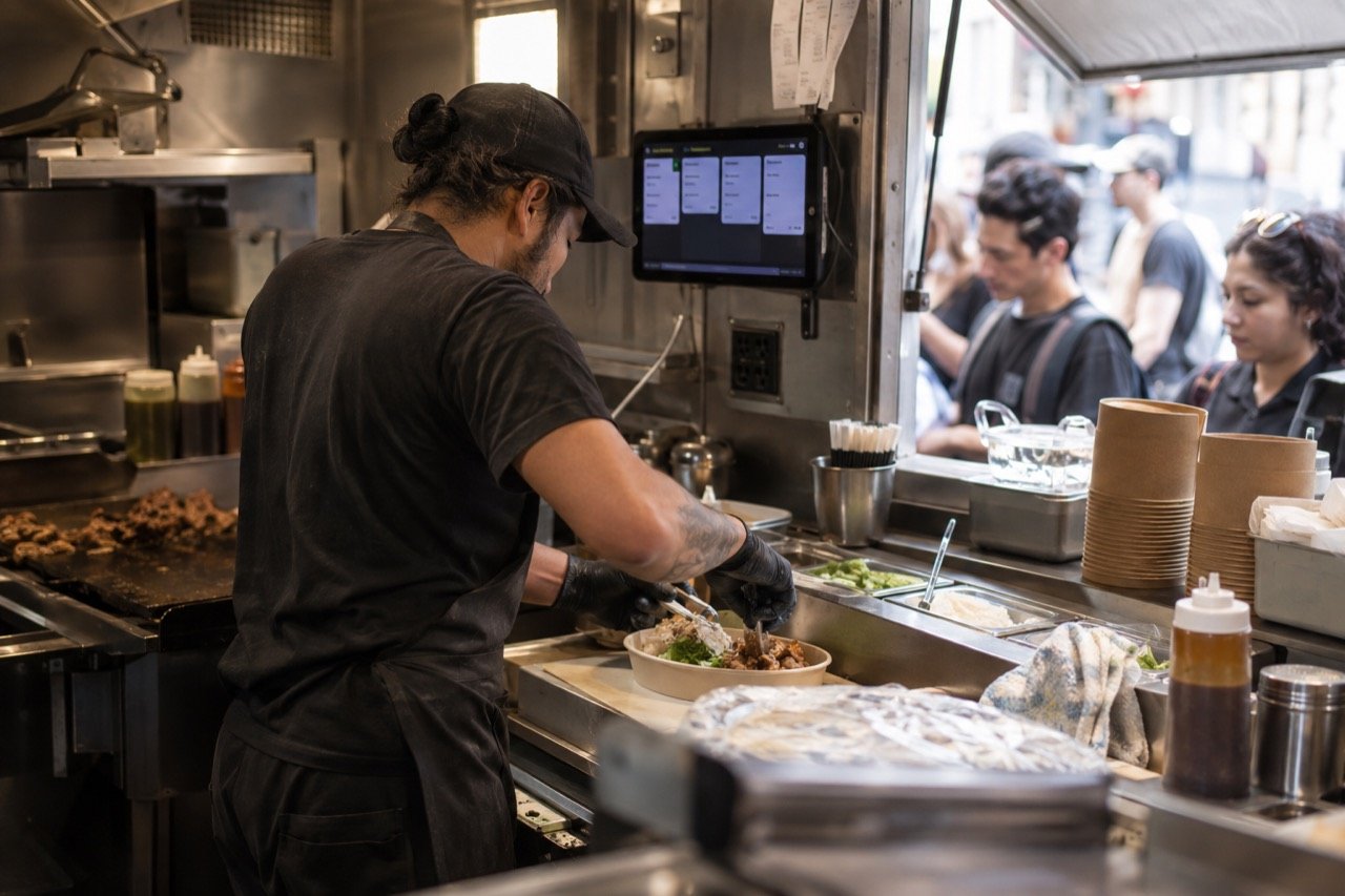 A food truck cook reads the next order on a tablet mounted inside the truck