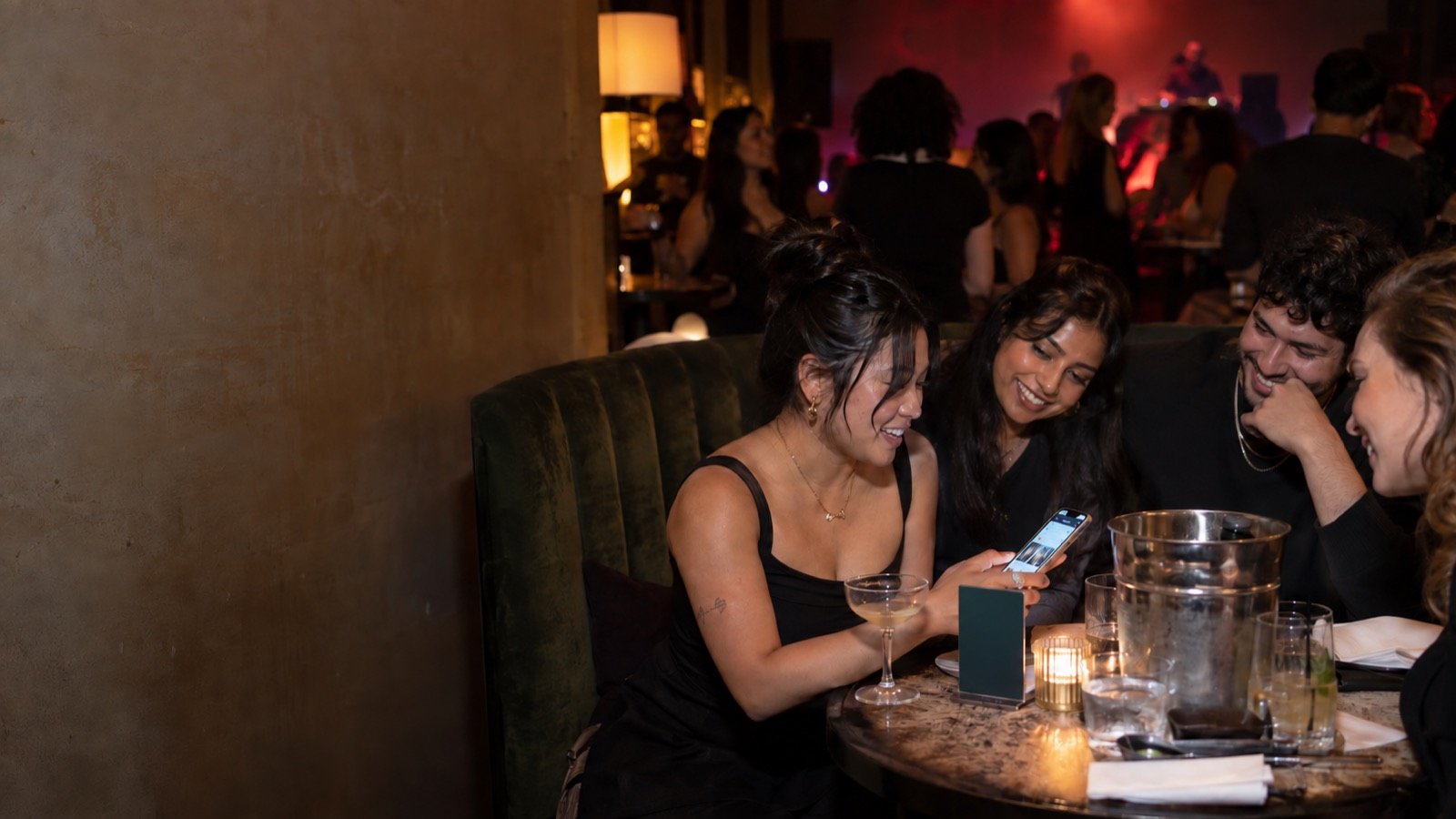 A group in a lounge booth orders the next round by tapping the printed display on their table