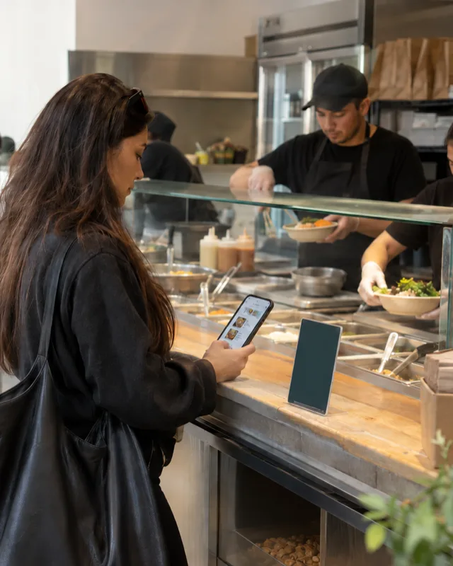 A customer orders from her phone at an NYC steam table lunch counter