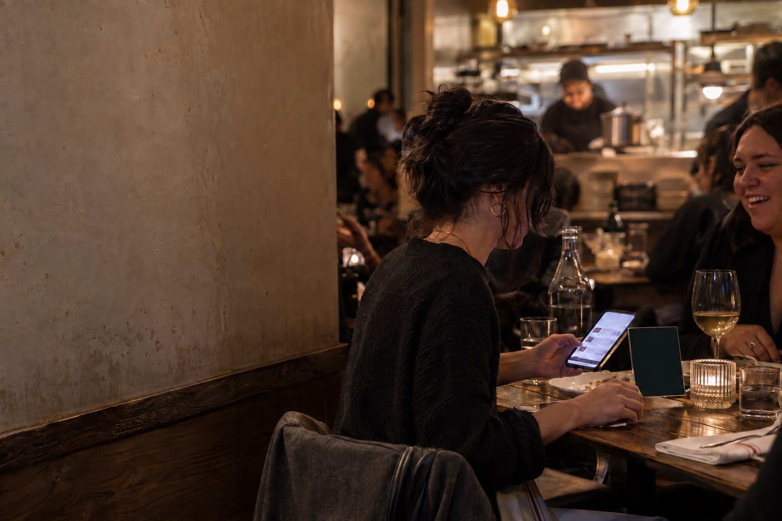A guest taps her phone on a printed table display to order at a busy New York restaurant